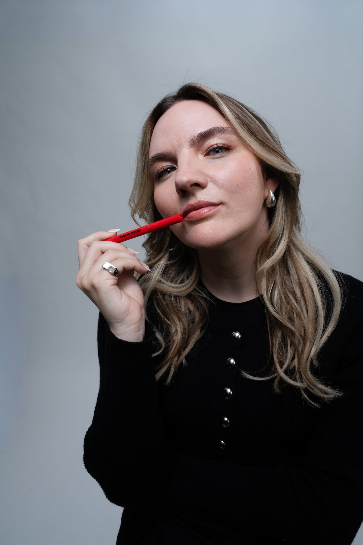 Frau hält The Lip Liner hoch vor grauem Hintergrund